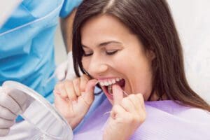 woman flossing her teeth at the dentist office